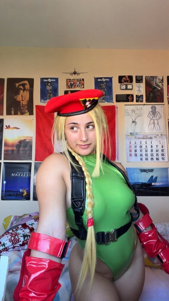 Bulkykrispis in Cammy White cosplay sitting in her bedroom in front of a fitness poster wall