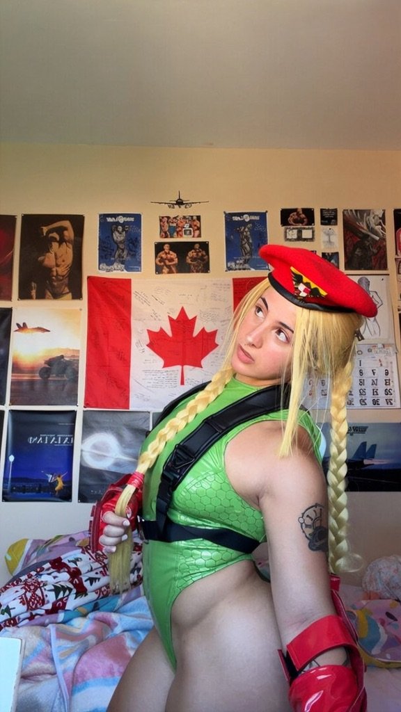 Bulkykrispis in Cammy White cosplay posing in front of a Canadian flag on her bedroom wall