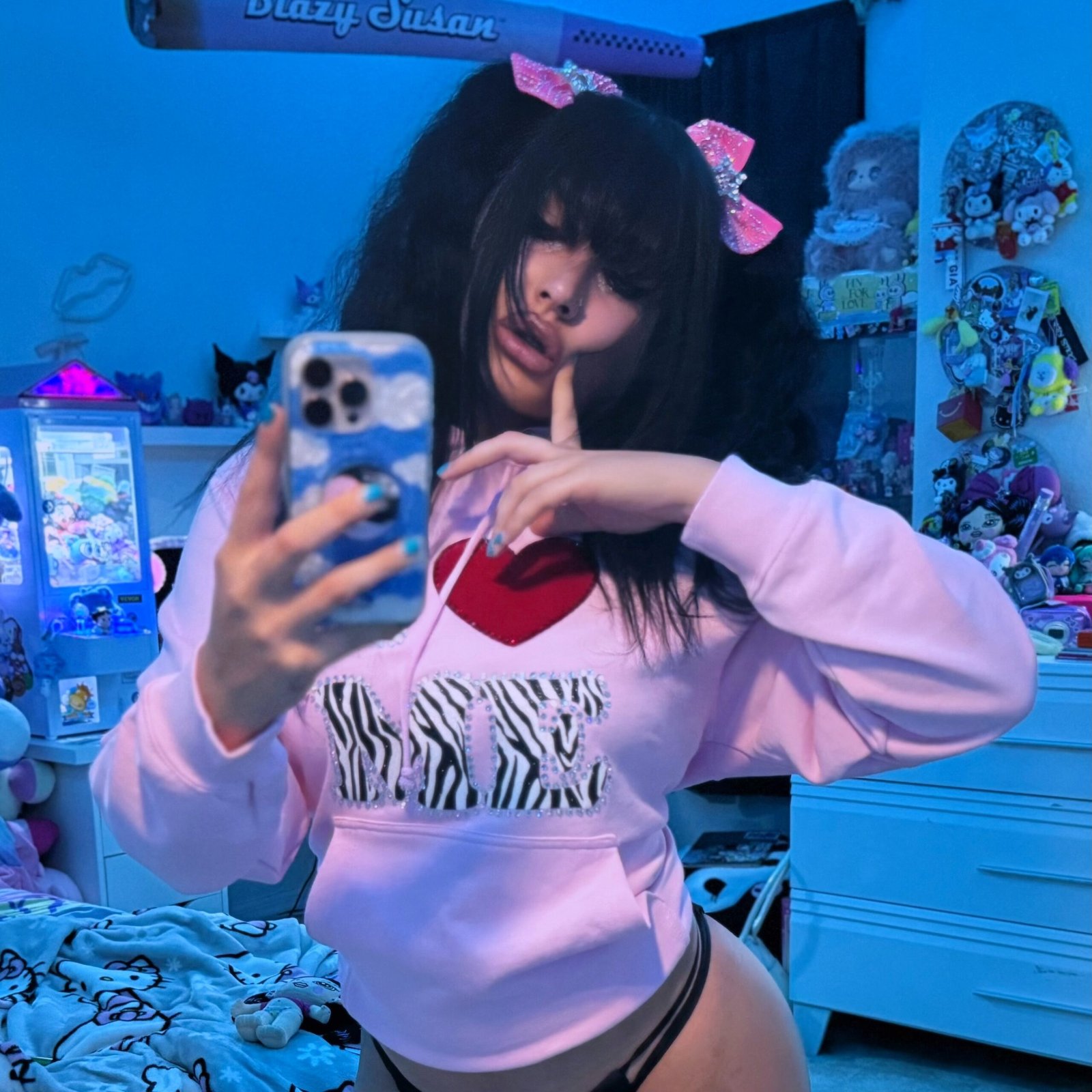 Lord Len leans towards the mirror in a pink hoodie with her plushie on her shoulder and a Hello Kitty neon light behind